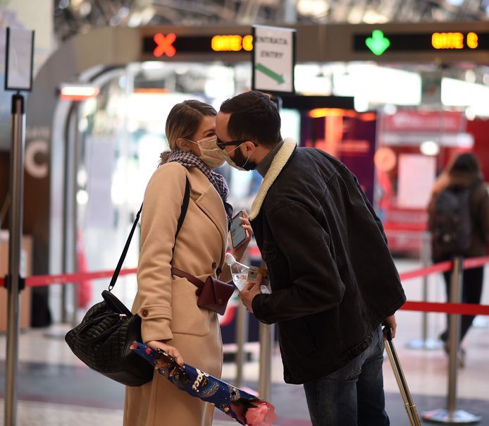 Een gek beeld in het Centraal-Station van Milaan gisteren: twee mensen die een masker dragen, geven elkaar toch een kus.