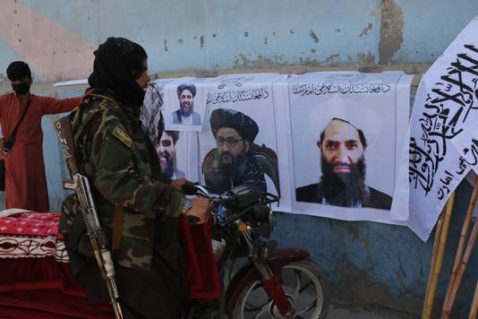 Een talibanstrijder bekijkt posters en vlaggen van talibanleiders in Kaboel.