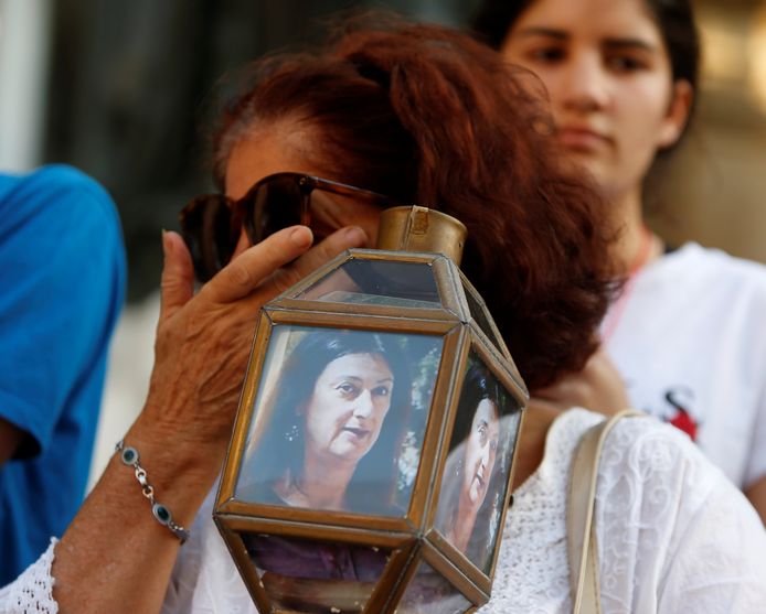 Een vrouw draagt een lantaarn met foto's van Daphne Caruana Galizia, tijdens een betoging tegen de moord op de onderzoeksjournaliste.