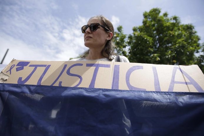 Een demonstrante houdt een spandoek omhoog met 'justicia' erop geschreven, gerechtigheid.