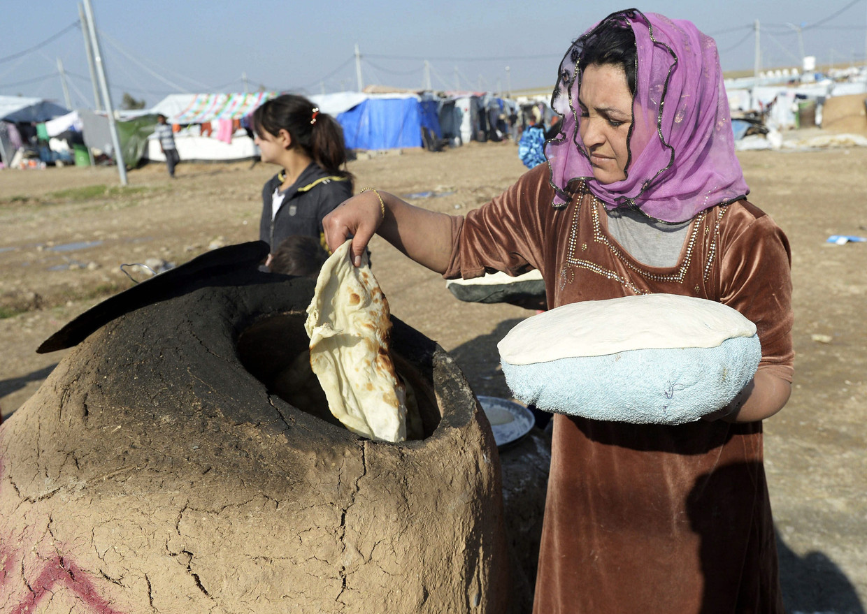Een Yezidi-vrouw bakt traditioneel brood in een vluchtelingenkamp. Beeld EPA