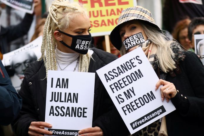 Medestanders van Assange steunen hem met bordjes buiten de rechtbank.