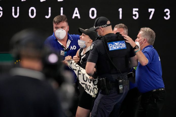 Police and security take a protester who jumped onto Rod Laver Arena away during the men's singles final match between Rafael Nadal of Spain and Daniil Medvedev of Russia at the Australian Open tennis championships, in Melbourne, Australia, Sunday, Jan. 30, 2022. (AP Photo/Simon Baker)