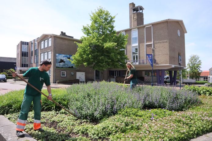 Robert Jansen (links) en Rob Hille zijn aan het wieden bij het gemeentehuis in Oostburg, een van de locaties die op de schop gaat.