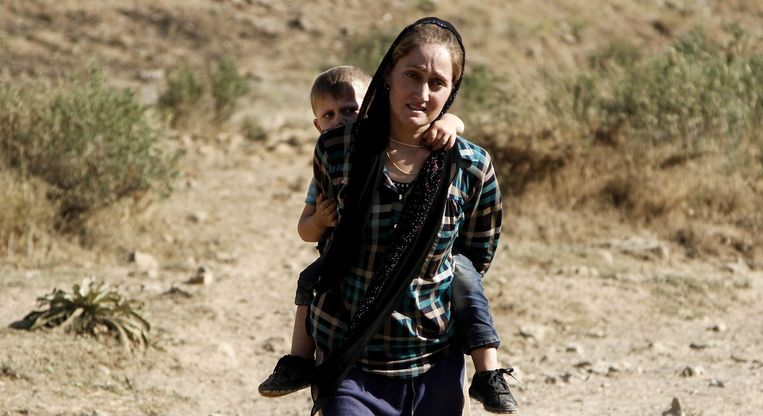 Een vrouw van de yezidi-geloofsgemeenschap vlucht met haar zoon op haar rug naar de stad Sirnak, bij de Turks-Iraakse grens in augustus 2014. Beeld EPA