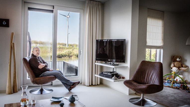 Bewoner Maurice Bakker met voor zijn deur één van de gewraakte windmolens. Beeld Jörgen Caris