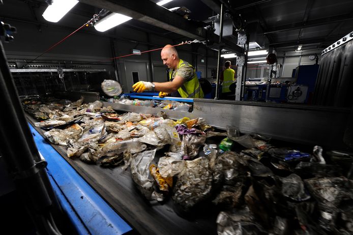 Een medewerker van Omrin in Friesland sorteert plastic op een van de lopende banden in het bedrijf.