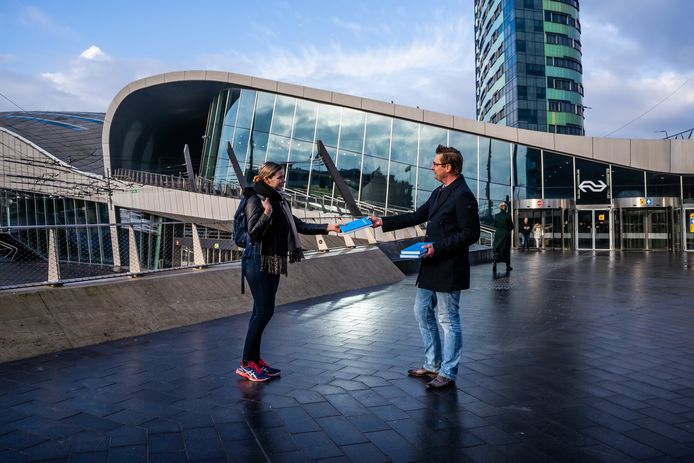 Als alternatief voor een officiële boekenpresentatie deelt Menno Loos (r) op de eerste dag van de verschijning zijn boek uit aan passanten bij station Arnhem Centraal, in dit geval aan de 22-jarige Sascha de Wijk (l) uit Huissen.