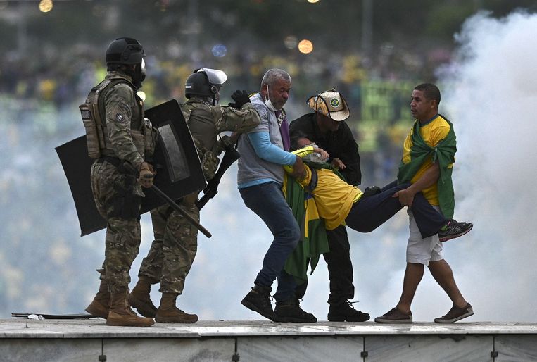 Politie-agenten verdrijven Bolsonaro-supporters later op zondag bij het presidentieel paleis. Beeld ANP / EPA