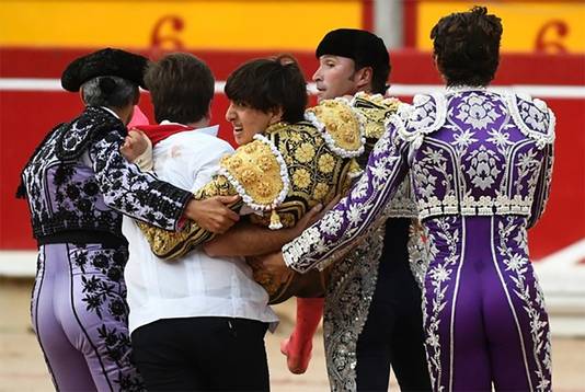 De gewonde stierenvechter wordt uit de arena gedragen.