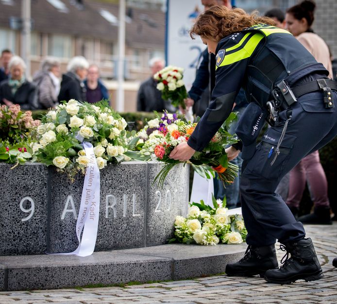 De herdenking van 2016.  Een politieagent legt bloemen bij het monument ter nagedachtenis aan de slachtoffers van het schietdrama in winkelcentrum de Ridderhof.
