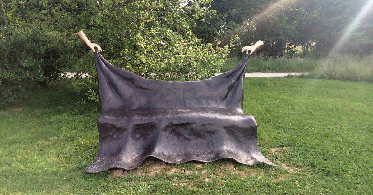 Twee handen houden zwevende bank bij kerk Noordwelle in de lucht