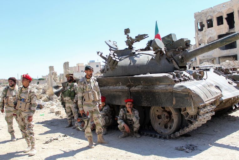 In de kapotgeschoten straten van Hajar al-Aswad verzamelen acteurs, verkleed als soldaten, zich bij een tank.  Beeld Reuters