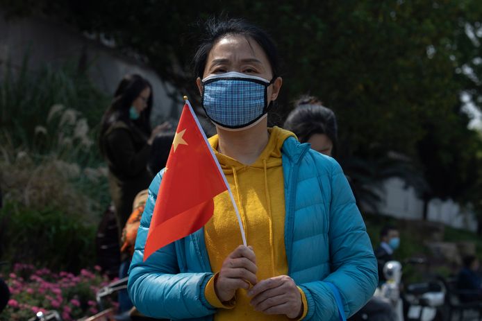 Une femme tenant un drapeau national chinois près d'un site de recueillement en hommage aux victimes du nouveau coronavirus à Wuhan.