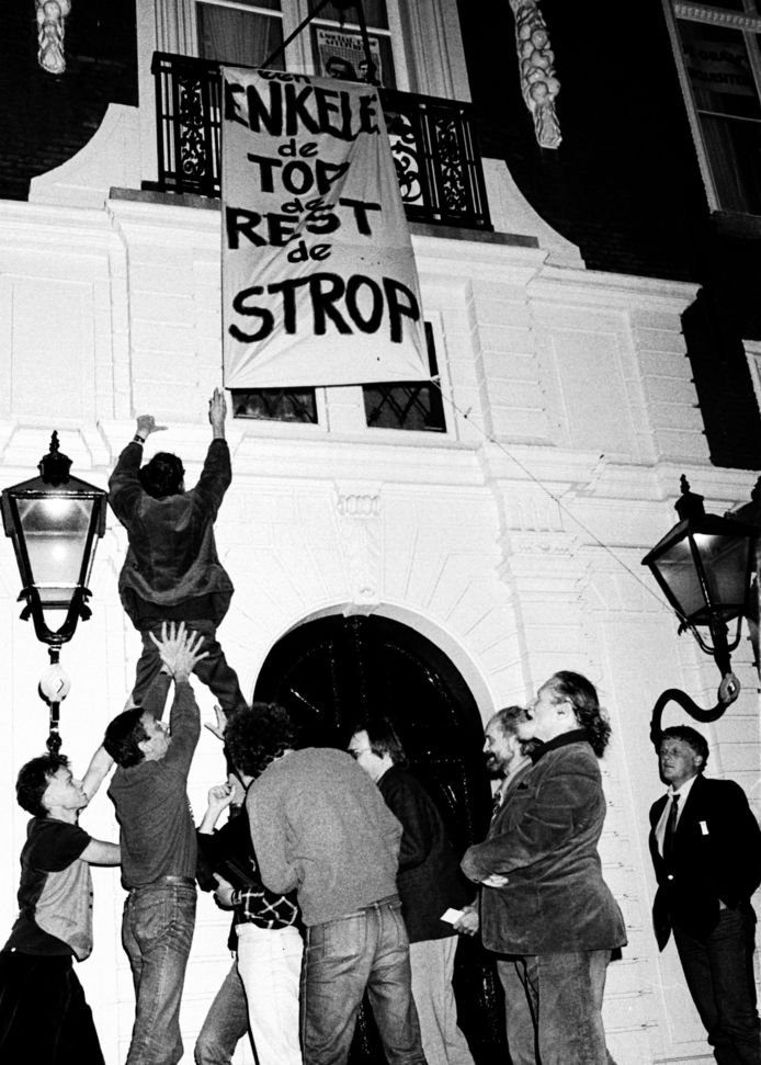 De actievoerders hangen op 16 november 1986 een spandoek boven de deur van het Johan de Witthuis. Leo van der Velde (rechts) ziet erop toe.