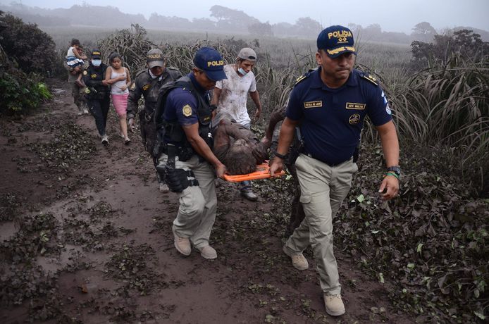 Politieagenten dragen een door de vulkaanuitbarsting gewond geraakte man op uit het getroffen dorp El Rodeo.
