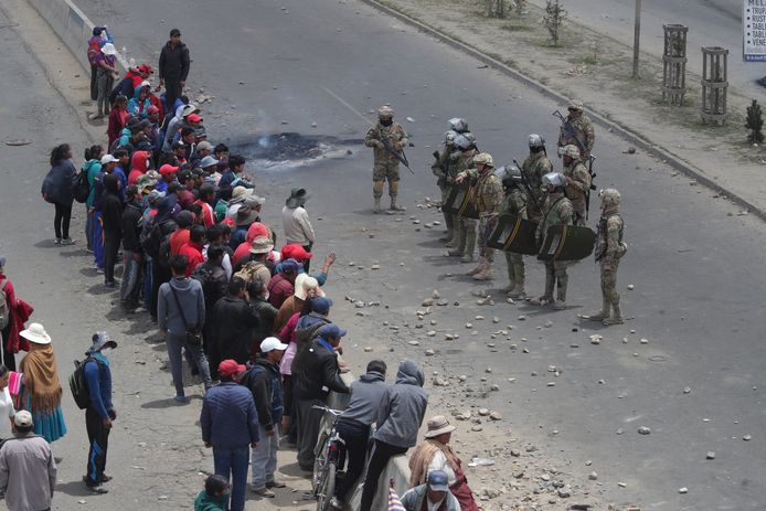 Een groepje demonstranten staat tegenover gewapende ordediensten in El Alto, Bolivia.