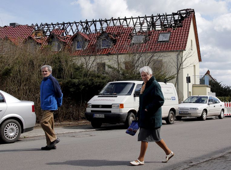 Inwoners van Tröglitz lopen langs een gebouw waarin asielzoekers opgevangen zouden worden. Het is door brand verwoest. Beeld reuters