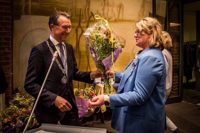 Bloemen en een koninklijke onderscheiding, uit handen van burgemeester Jan Pierik voor VVD-raadslid Anka Jacobs.