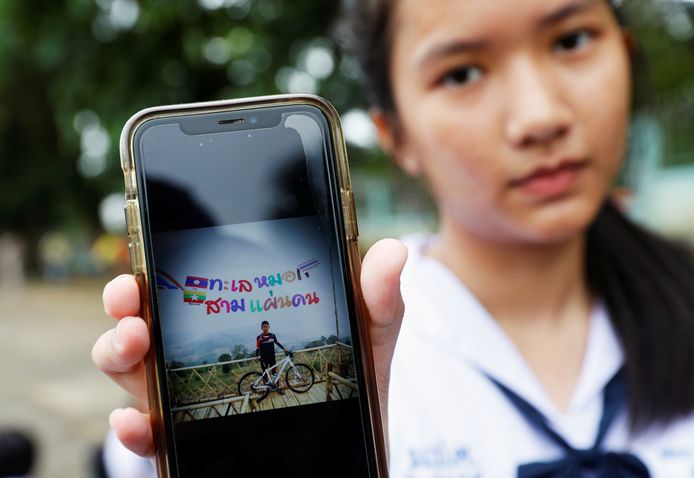 Een klasgenote van  Prachak Sutham (13), een van de vermiste voetballers, toont een foto van hem op haar smartphone. Heel Thailand leeft erg mee met het nieuws.