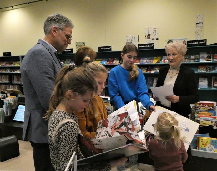 Terwijl kinderen in prentenboeken snuffelen, biedt Marianne Spierings (rechts) wethouder Bert van Druenen (links) een petitie aan met 557 handtekeningen om de bibliotheek te verplaatsen.