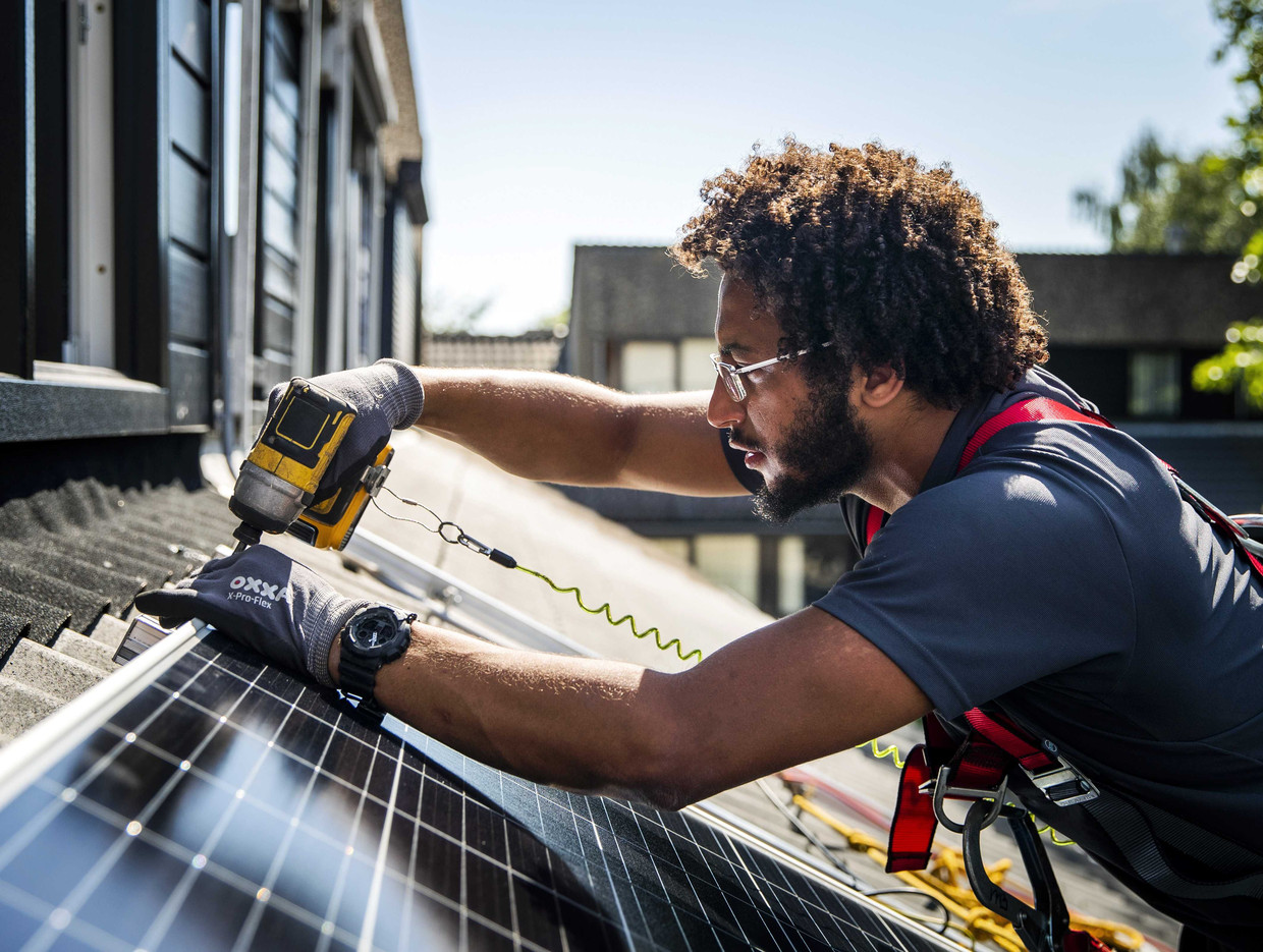 Een installateur plaatst zonnepanelen op het dak van een woonhuis. Beeld ANP