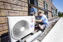 Een installateur plaats een airconditioner in een woning. Niet alleen geschikt voor verkoeling, maar ook voor verwarming.