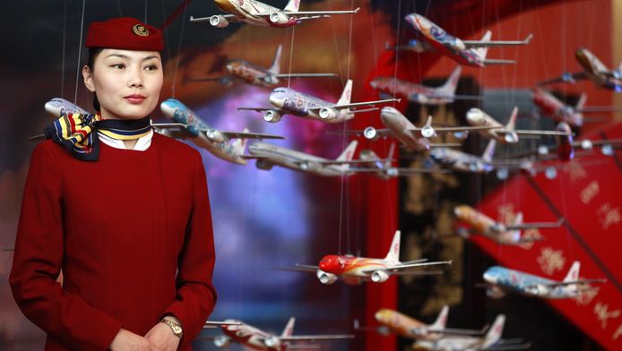 Een Chinese stewardess staat naast modelvliegtuigjes op de jaarlijkse algemene vergadering van de International Air Transport Association