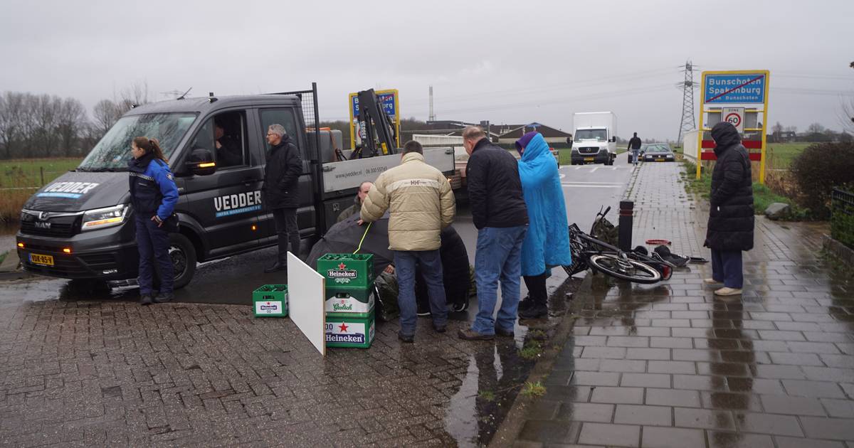 Omwonenden maken overkapping van bierkratjes en paraplu om aangereden fietser te beschermen tegen kou.