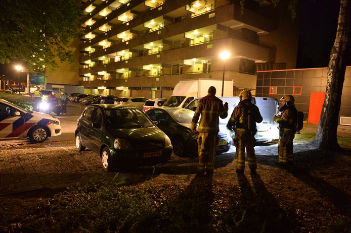 De brandweer bekijkt met een zaklamp de schade aan de auto die in de brand stond.