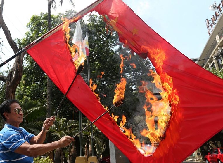 Een Filipijnse man verbrandt de Chinese vlag om te proteteren tegen de Chinese expansiedrift. Beeld EPA