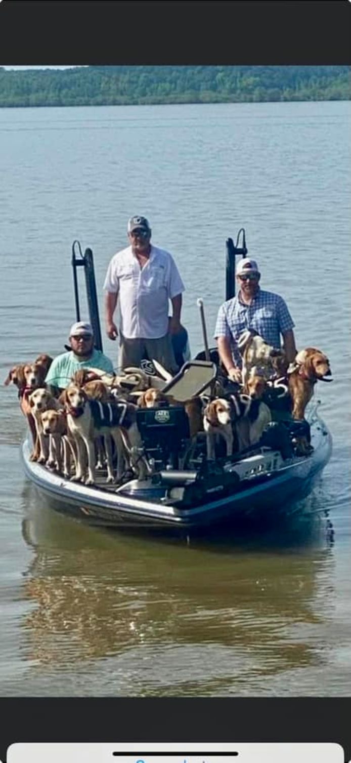 De drie redders met een hoop honden op hun kleine bootje.