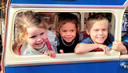 Noortje, Tess en Liam laten zich met plezier in de bus rondrijden op de Vlissingse kermis.