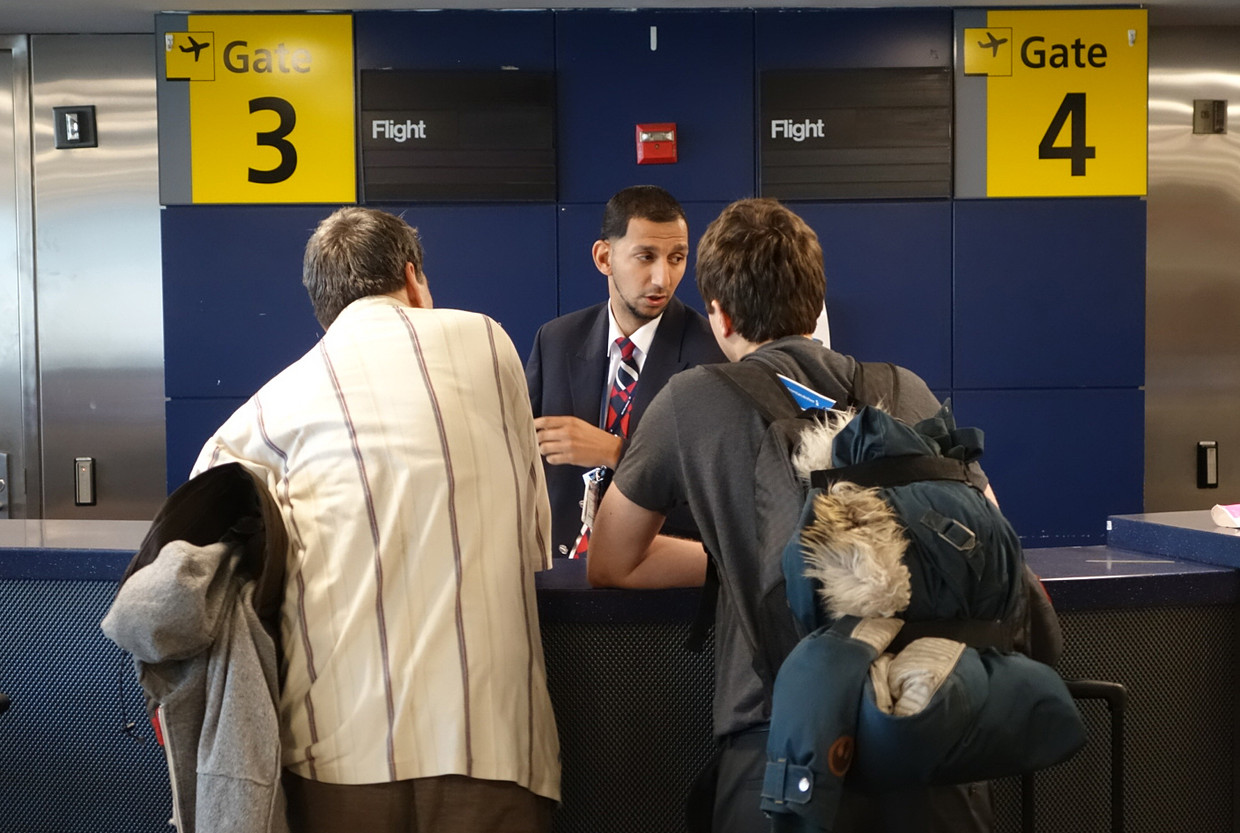 Een baliemedewerker van British Airways op New York JFK geeft passagiers informatie over hun vlucht. Beeld AFP
