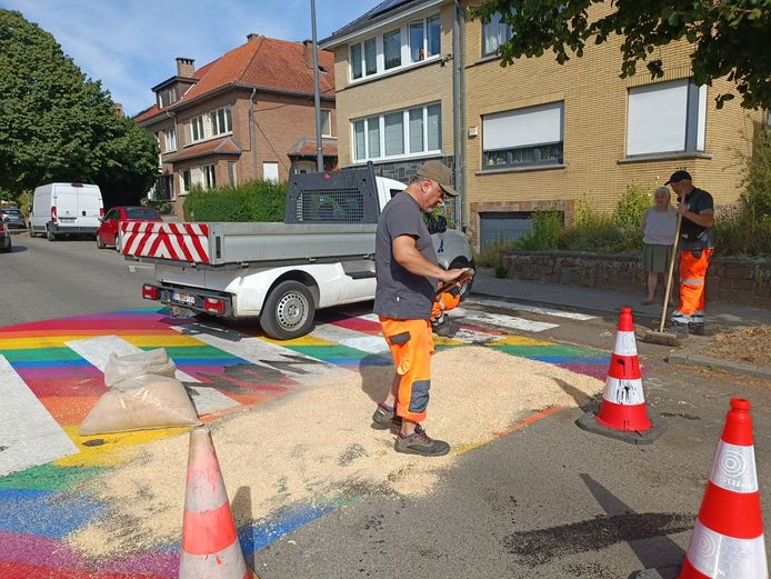 Gemeentewerkers wissen snel de beledigende boodschappen op het nieuwe regenboogzebrapad.