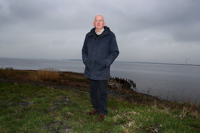 Henk Bos bij de Palendijk langs de kust  van Spakenburg. Aan de overkant Flevoland met windmolens. Daar zou hij graag een groter meer zien. ,,Het zijn tenslotte ónze oude visgronden.”