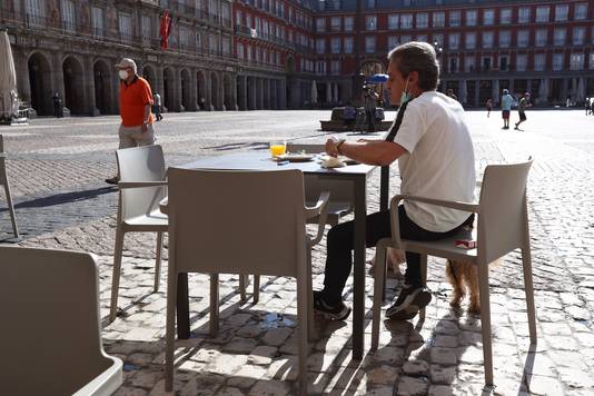 In Spanje hebben sommige restaurants opnieuw de deuren geopend. Een man geniet van een glas fruitsap om de Plaza Mayor in Madrid.