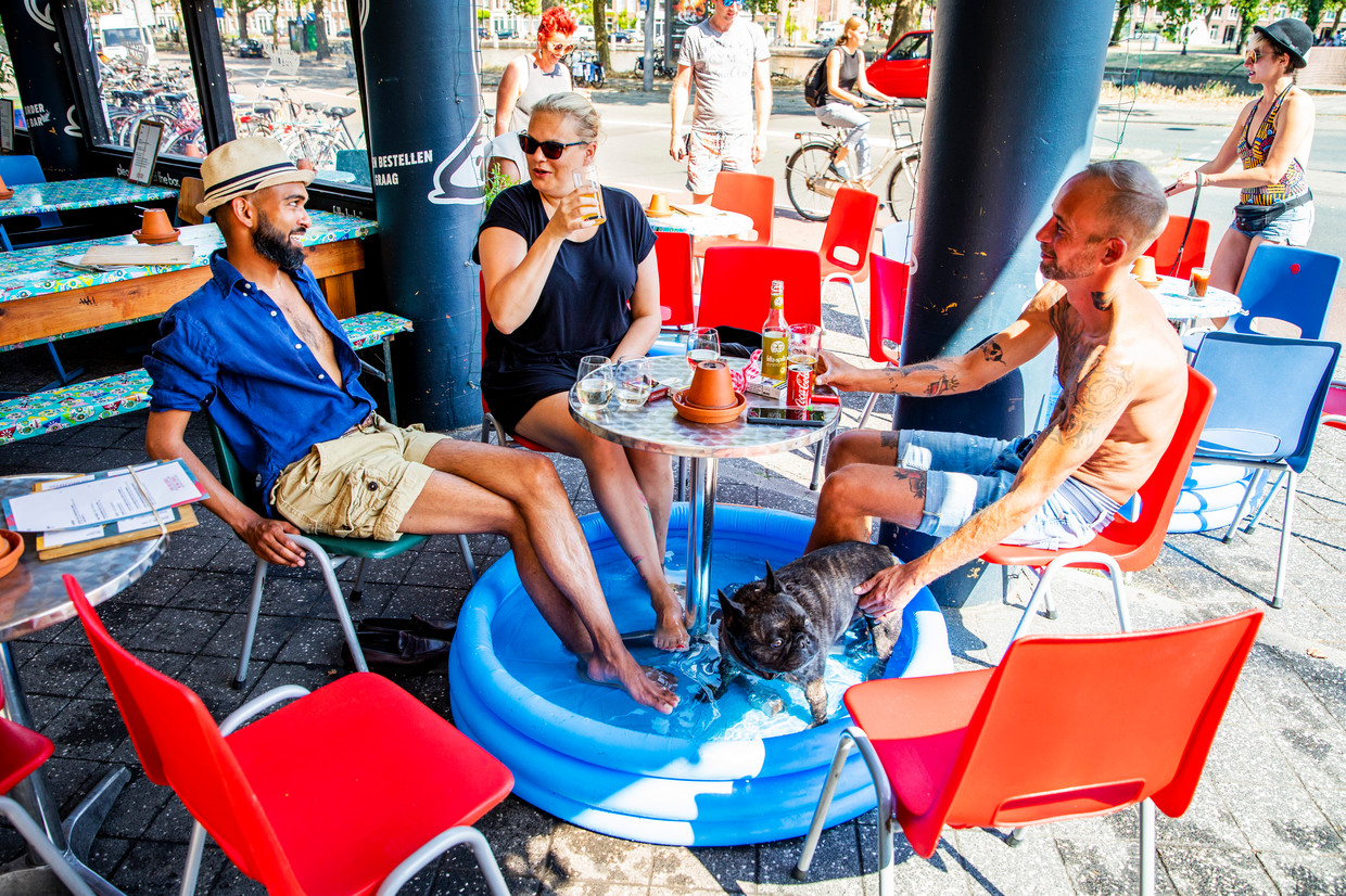Bezoekers van een cafe zitten met hun voeten in een zwembadje op een terras aan de Nassaukade in Amsterdam. Beeld ANP