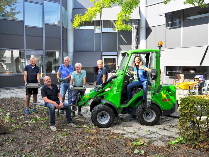De aanleg van de beleeftuin van verpleeghuis Keyserinnedael is begonnen. In de graafmachine Kim Bombeeck. Midden in het groene shirt Wim Swinkels van de Rotary Helmond. Foto Nienke van der Kruijs/fotomeulenhof