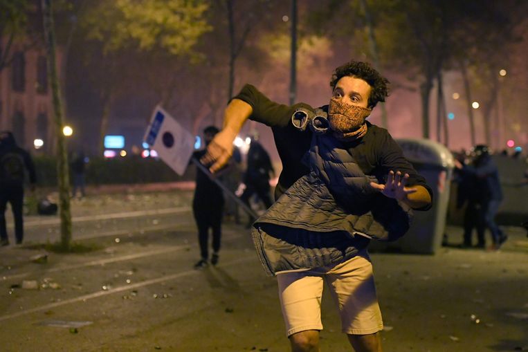 Een demonstrant gooit in Barcelona een voorwerp naar de oproerpolitie.  Beeld AFP