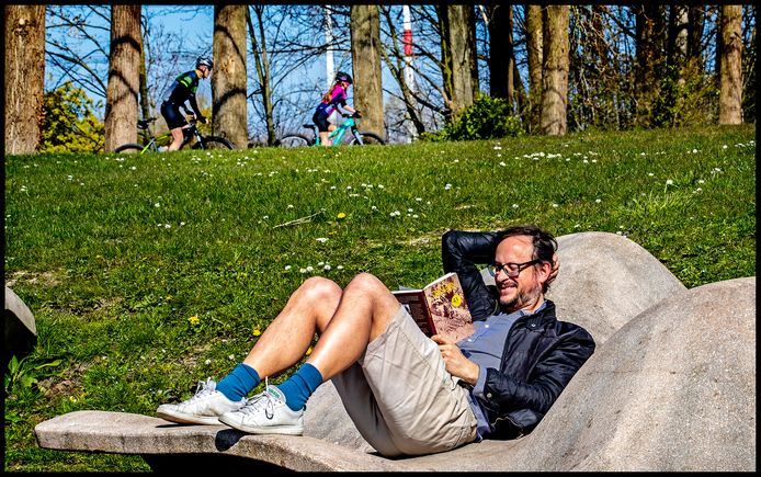 Over het algemeen is het rustig buiten, op de zonovergoten zondag. Deze meneer leest een boek in het Haarlemmermeerse Bos, terwijl op de achtergrond een vader met zijn dochter een mountainbike-parcours aflegt