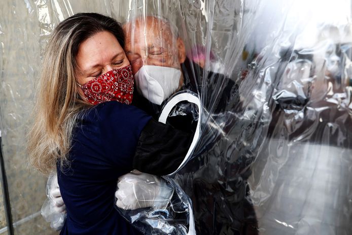 Maria Paula Moraes knuffelt haar 82-jarige vader. De twee zijn vanwege het coronavirus gescheiden door een 'knuffelgordijn' in Sao Paulo, Brazilië.