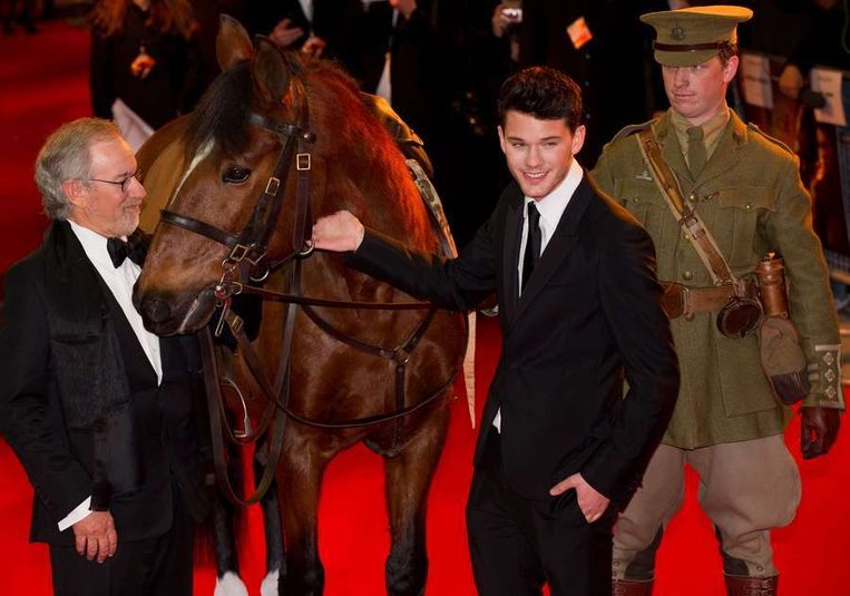 Steven Spielberg (links) en hoofdrolspeler Jeremy Irvine (tweede van rechts) gisteren met het paard 'Joey' bij de première van War Horse. Beeld afp