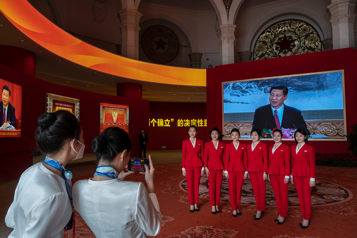 Hostessen poseren met op de achtergrond Xi Jinping. Beeld Getty Images