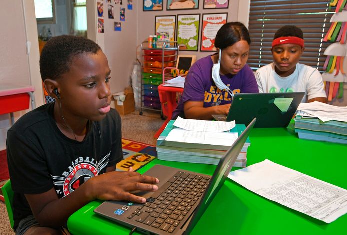 Kinderen volgen thuis les via de computer.