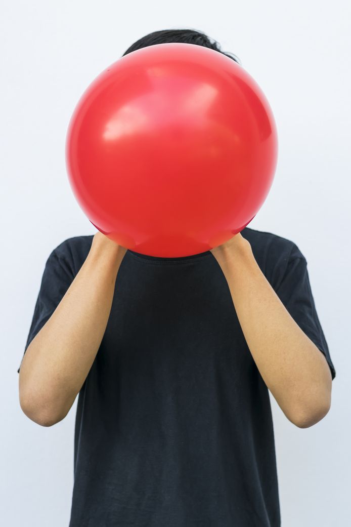 Een jongere neemt wat lachgas tot zich via een ballon gevuld met het spul.