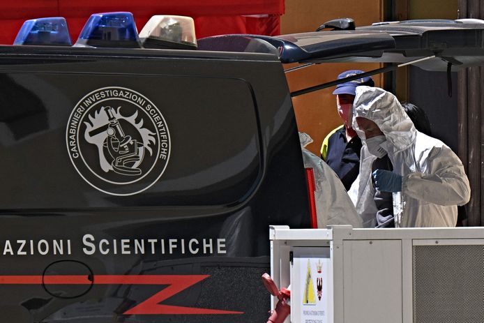 Een forensisch medewerker van de Carabinieri bij een koelwagen met de lichamen van mensen die omkwamen in de lawine.