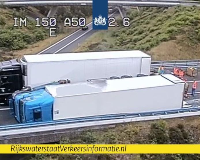 De lading van de gekantelde vrachtwagen wordt in een andere vrachtauto overgeheveld.