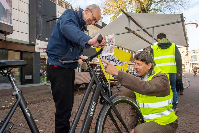 Hein Moens van de Fietsersbond Hengelo repareert een voorlamp van een voorbijganger.