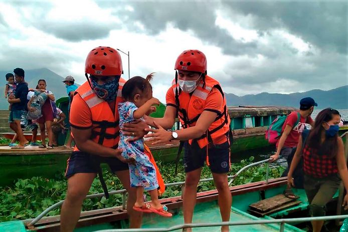 Leden van de Filipijnse kustwacht dragen een kind aan boord van een boot waarmee inwoners van de provincie Camarines Sur naar veiligere oorden worden gebracht.